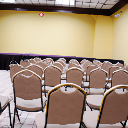 תמונה של אולם אירועים קטן עם כיסאות ושולחנות ערוכים לפגישה